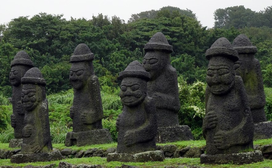 Dieses Bild zeigt einige Dol hareubang wobei es sich um klassische Stauten aus Vulkangestein handelt die überall auf Jeju zu finden sind